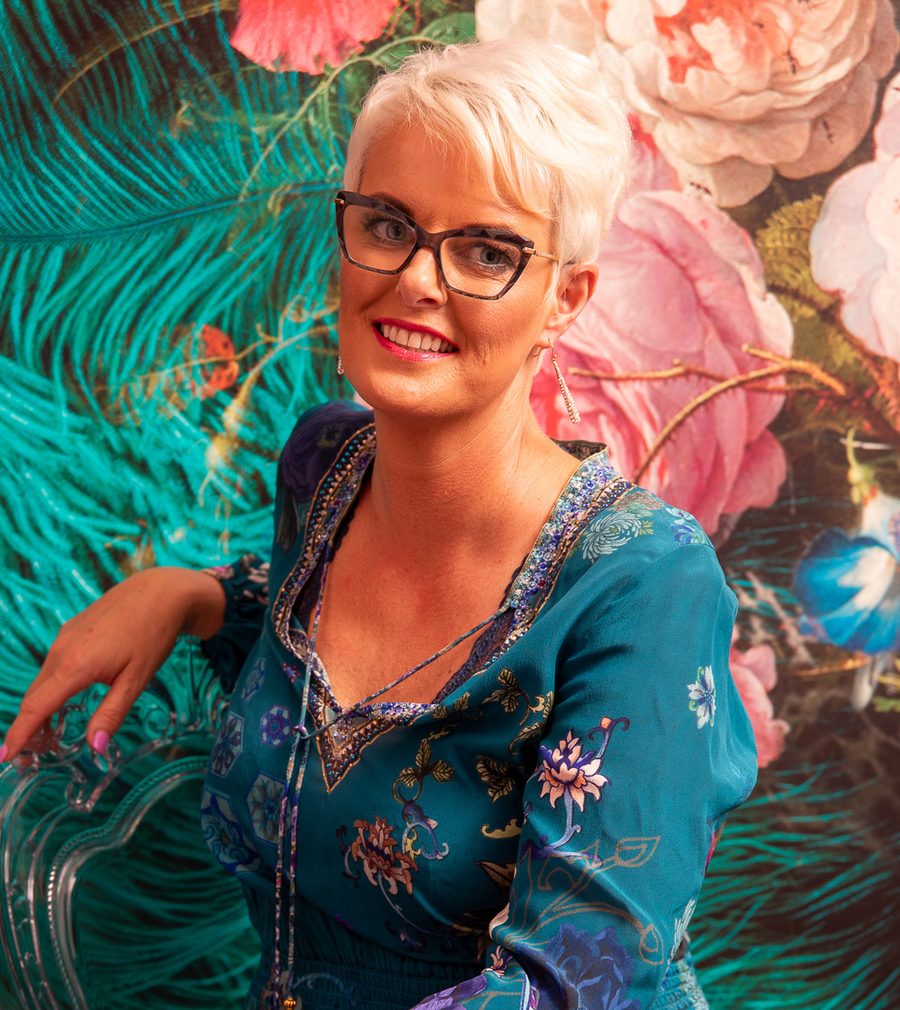 Vicki in an embroidered teal dress against Victoria Jane floral wallpaper