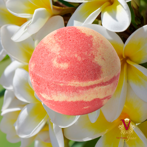 Tilley - Mango Delight Luxurious Bath Bomb - 150g in front of bright colourful flowers