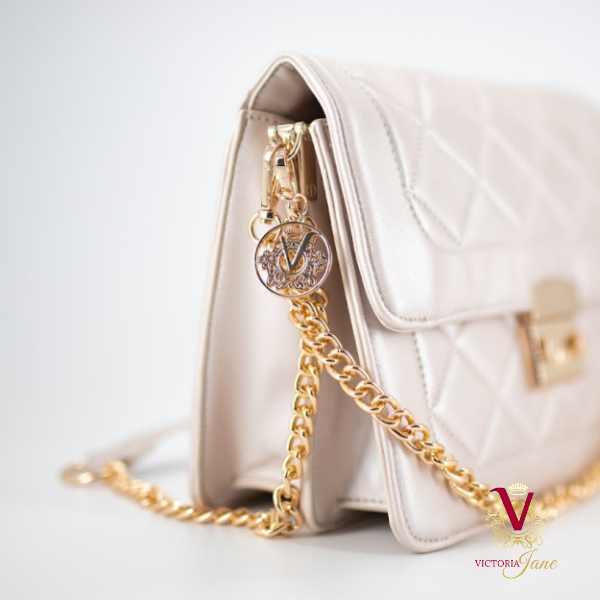 side view of chain logo of Champagne Metallic Quilted Cross Body Bag on white background with victoria jane logo