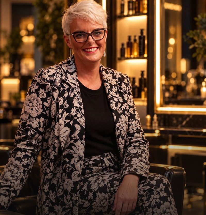 Vicki seated in a black leather chair in the new salon