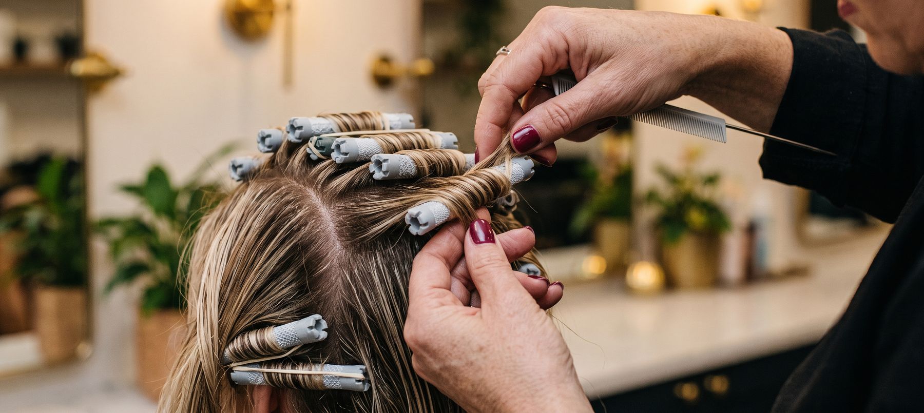 A stylist setting hair on perm rollers at V For Hair